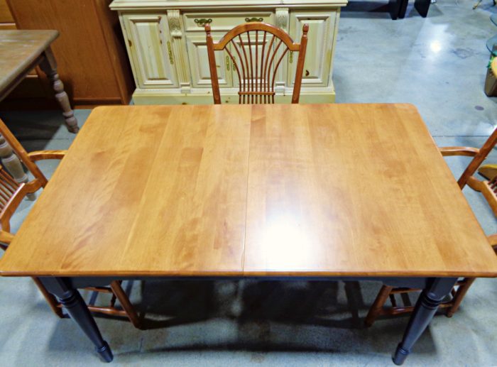 Maple dining table with black painted base and four dining chairs.